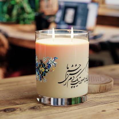 Candle with decorative label featuring Farsi calligraphy and floral designs on a white background