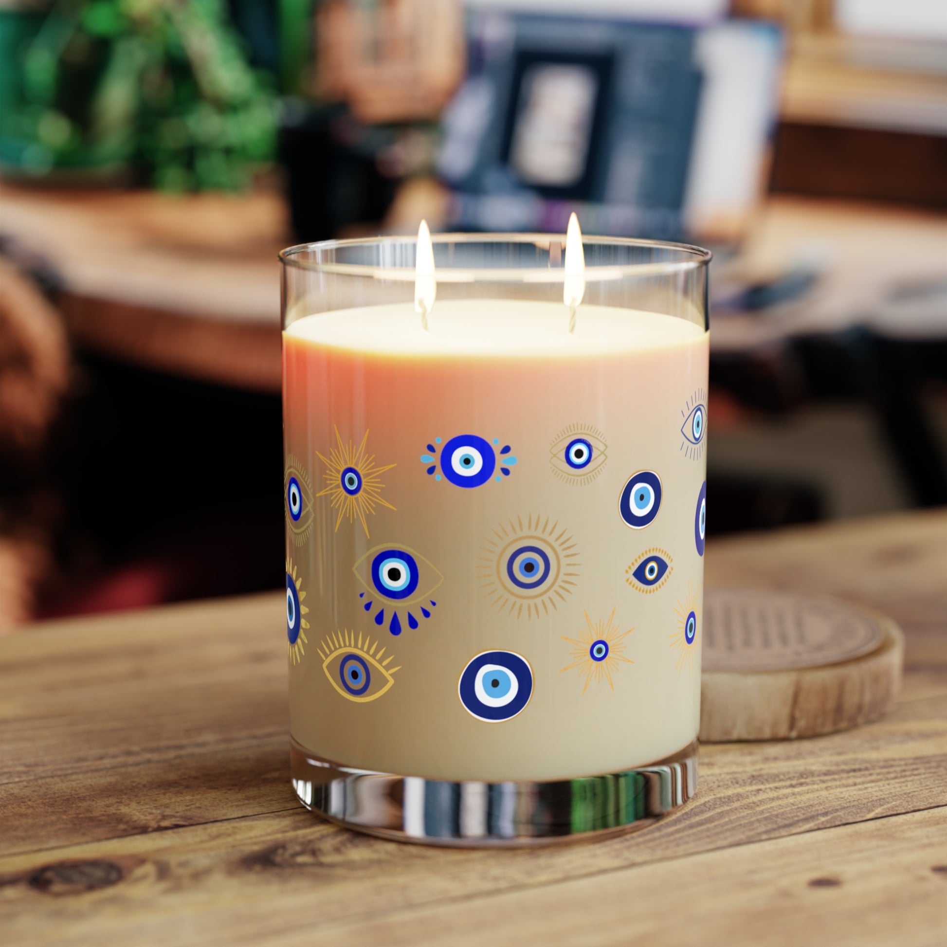 Candle with decorative evil eye design on a wooden surface