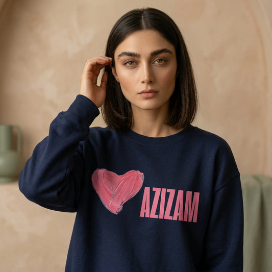 Woman wearing a navy sweatshirt with Azizam verbiage and heart graphic next to it. 