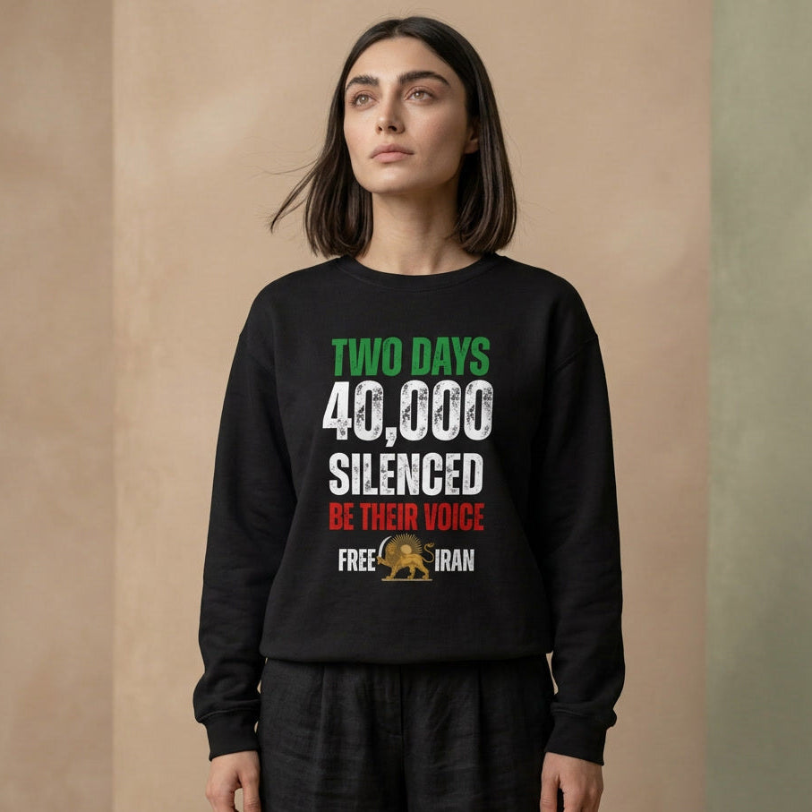 A woman wearing a black crewneck sweatshirt with a political graphic that reads 'TWO DAYS 40,000 SILENCED BE THEIR VOICE FREE IRAN' in green, white, and red, paired with black pants, set against a neutral beige background.
