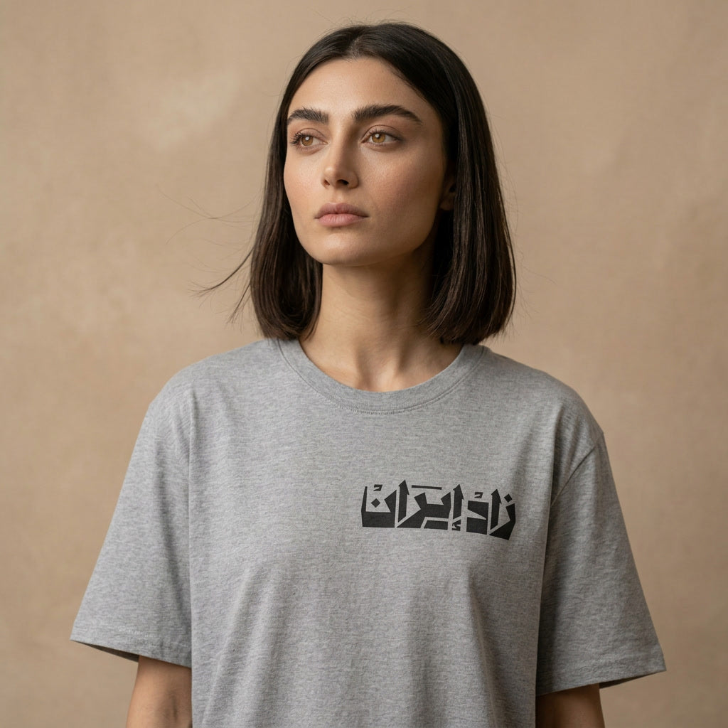 Woman wearing a gray t-shirt with Farsi text on a beige background