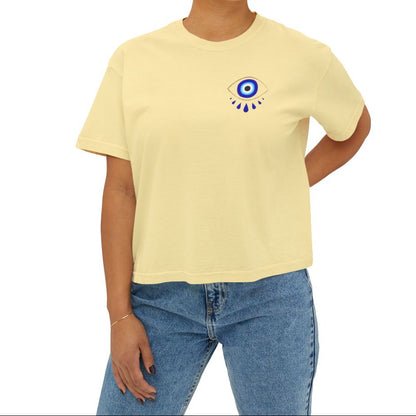 Person wearing a yellow t-shirt with an evil eye design on the chest on a white background