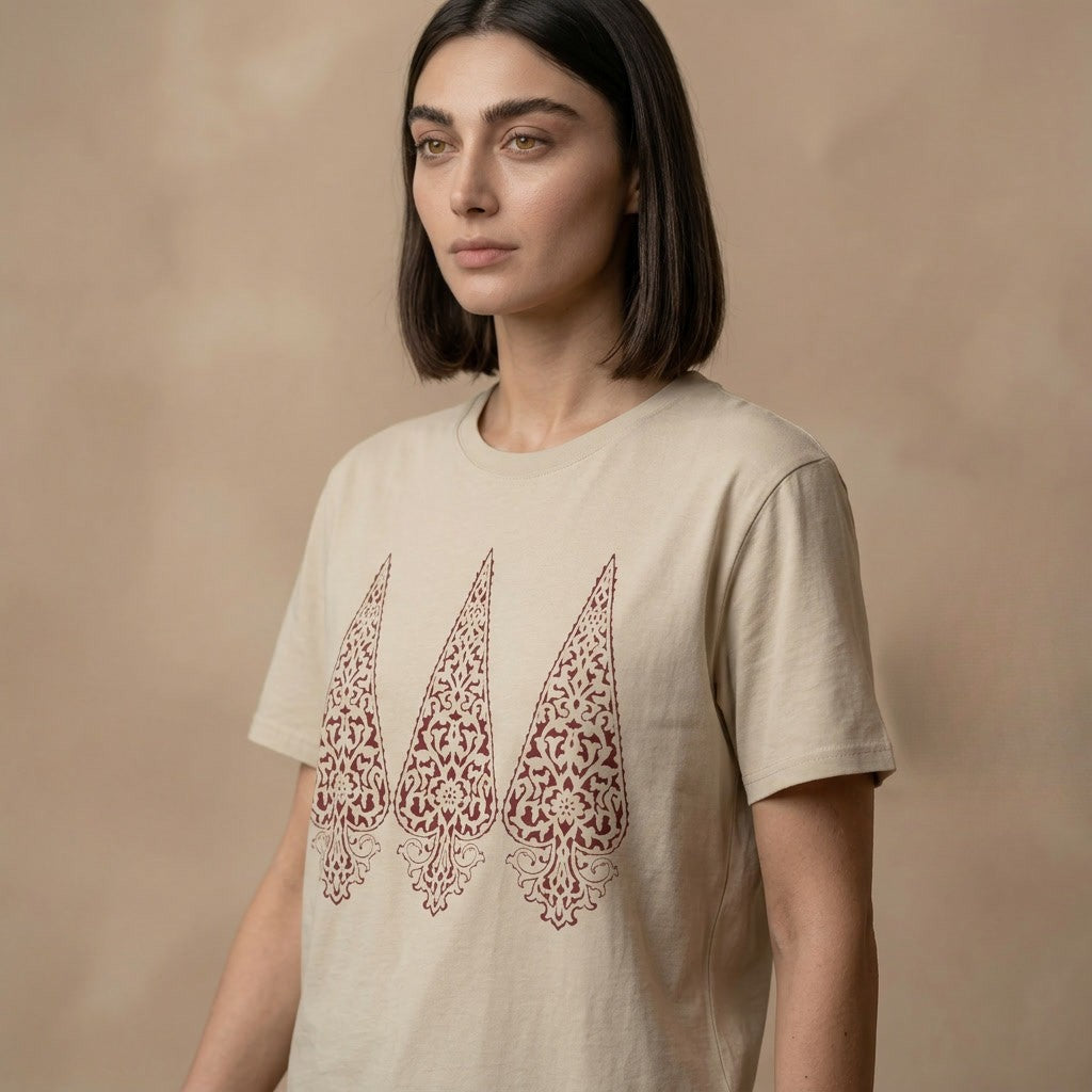 Woman wearing a beige t-shirt with red persian cypress designs on a brown background