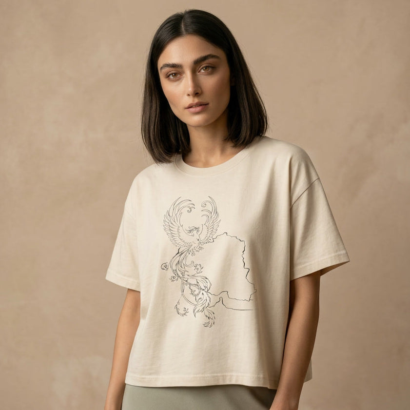 Woman wearing a beige t-shirt with a simorgh graphic design on a beige background