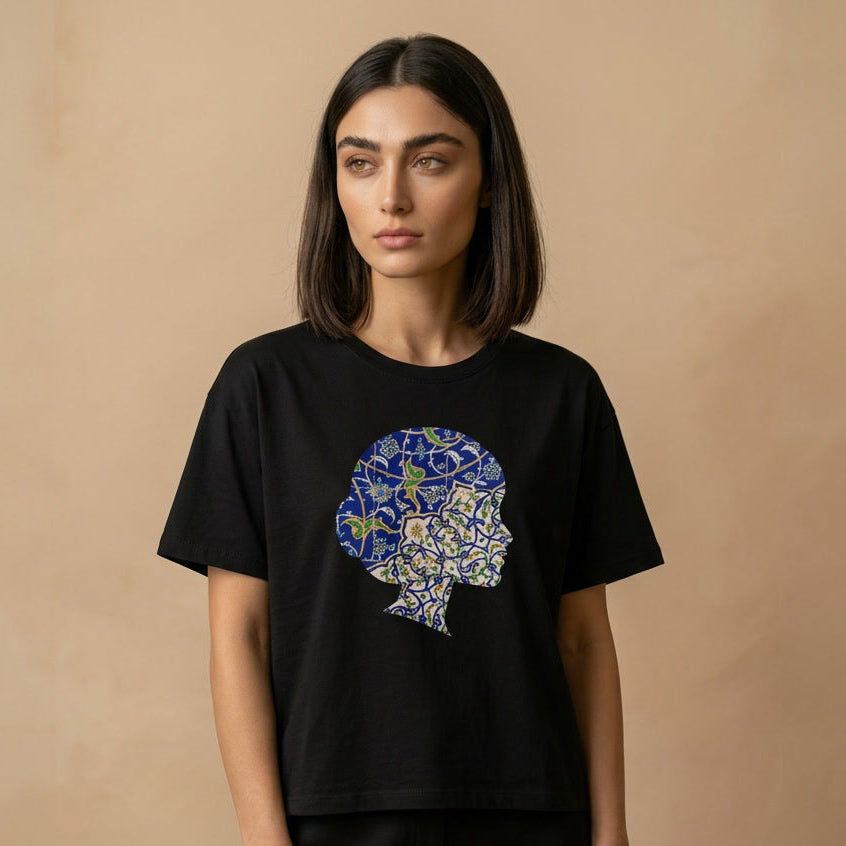 Woman wearing a black t-shirt with a colorful Persian tile design on a beige background