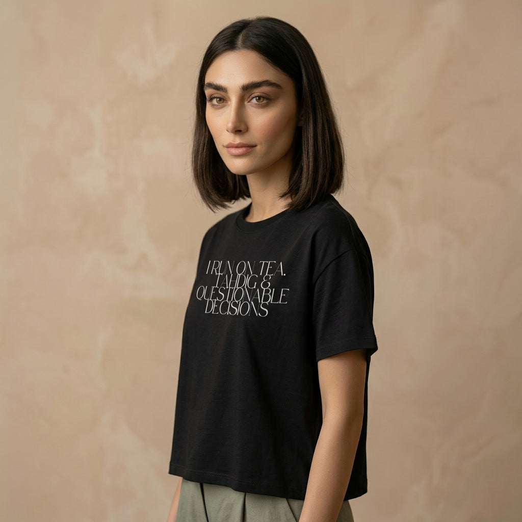 Person wearing a black t-shirt with I run on tea, tahdig & questionable decisions text on the chest. 