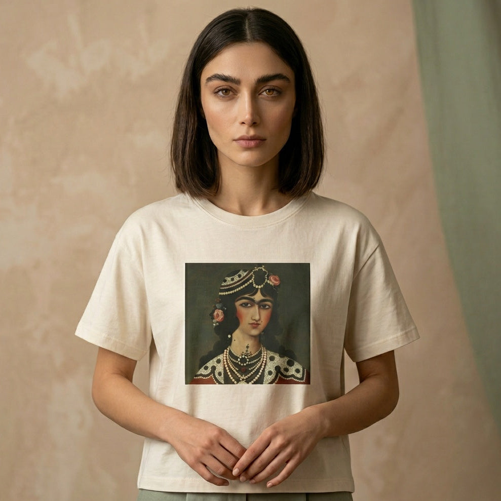 Person wearing a white t-shirt with a graphic of a Qajar woman's portrait on the chest on a beige background