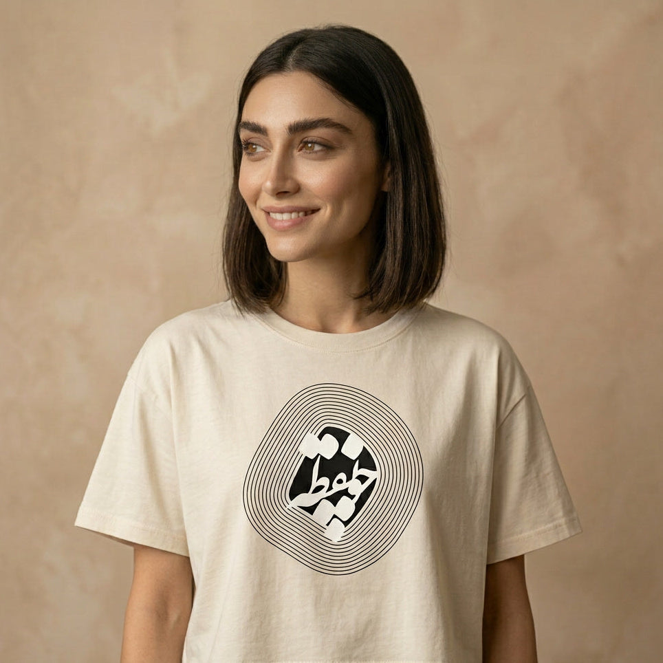Woman wearing a beige t-shirt with a graphic design and چو نقطه  in Farsi Persian on the chest on a beige background